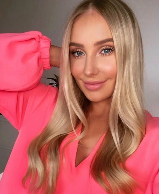 Blonde model wearing pink top showcasing smooth anti-frizz blonde hair